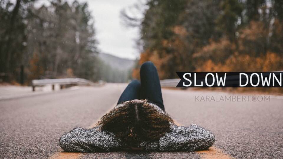 A woman on the road holding a sign that says "slow down".