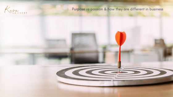 A red dart hits the bullseye on a target board in a blurred office setting. Text overlay reads, "Purpose vs passion & how they are different in business" with a logo in the top left corner.